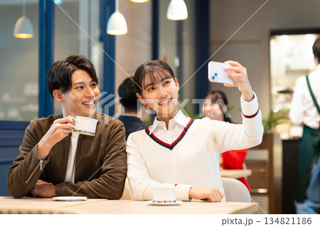カフェで写真を撮る若いカップル カフェで写真を撮る若いカップル 134821186