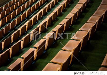 Background image of empty stands with multiple rows and empty seats. Orange fan seats are empty. News about fans and watching sports from stands. Cheering on your favorite sports team at stadium Background image of empty stands with multiple rows and empty seats. Orange fan seats are empty. News about fans and watching sports from stands. Cheering on your favorite sports team at stadium 134821336