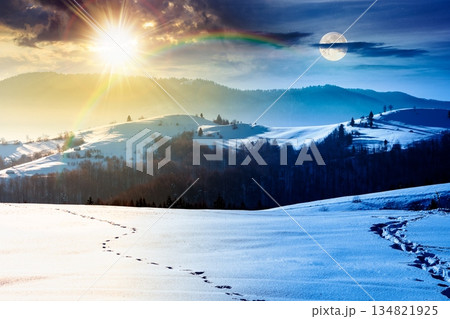 beautiful winter landscape with snow covered rolling hills. day and night time change concept. majestic mountains with sun and moon. frosty countryside scenery. harmony and progress calendar 134821925