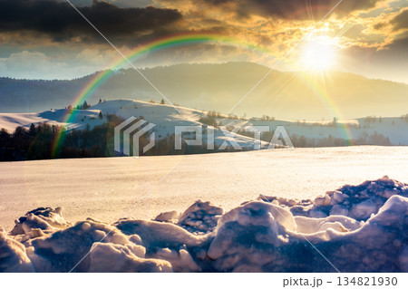 beautiful winter landscape with snow covered rolling hills under blue sky at sunset. majestic mountains in evening light. frosty countryside scenery. timeless nostalgia book cover with rainbow 134821930