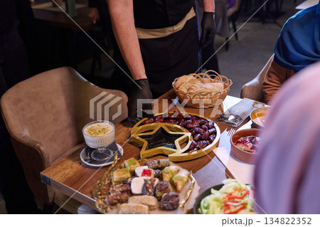 Muslim family shares iftar meal in a warm restaurant setting decorated for Ramadan celebration 134822352