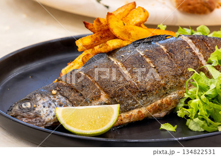 Roast trout with potatoes and lettuce salad 134822531