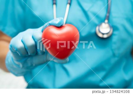 Doctor holding a red heart in hospital ward, healthy strong medical concept. 134824108