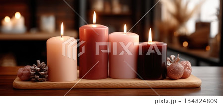 Decorative holiday arrangement with candles, ornaments, and pinecones set against a soft, glowing background 134824809