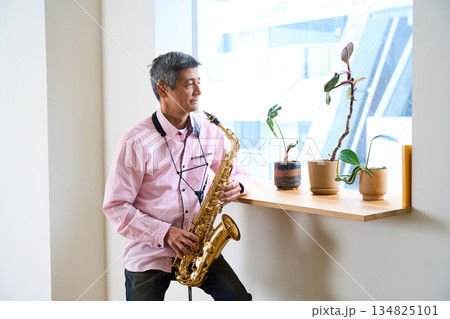 サックスを持って窓辺に佇む男性 134825101