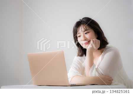 ノートパソコンを見る若いかわいい女性リラックスした嬉しい楽しい資格や勉強などの春色ピンクのイメージ ノートパソコンを見る若いかわいい女性リラックスした嬉しい楽しい資格や勉強などの春色ピンクのイメージ 134825161