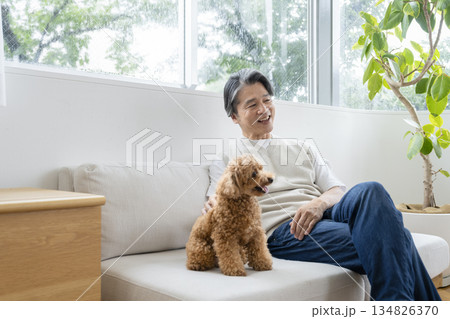ソファでくつろぐ50代の男性と犬　犬との暮らしイメージ 134826370