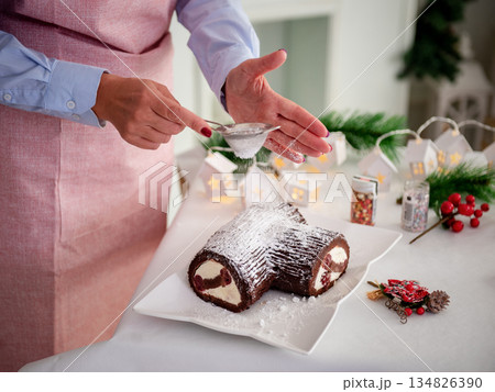 Chocolate cupcake on the New Year's table, Women's hands decorate the cake with powdered sugar. A festive concert 134826390