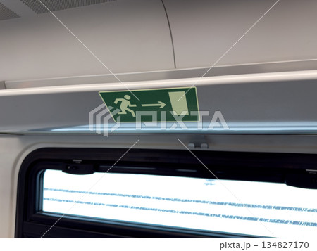 Sign showing person running toward exit of public transport hangs on luggage rack. Navigation in case of accident. Exit vehicle in case of fire or danger. Concept of rescue after accident Sign showing person running toward exit of public transport hangs on luggage rack. Navigation in case of accident. Exit vehicle in case of fire or danger. Concept of rescue after accident 134827170