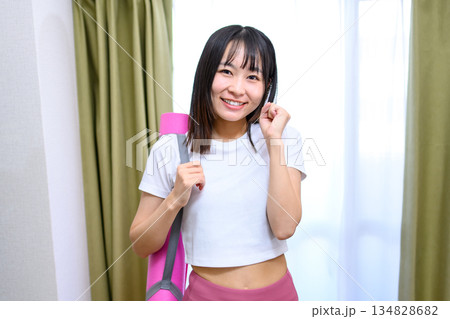 ヨガウェアでトレーニングジム、ヨガスタジオに向かう日本人女性　ヨガマット　レギンス　トリミングアップ 134828682