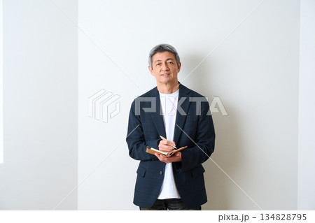 ジャケット姿で手帳にメモを取るシニア男性 134828795