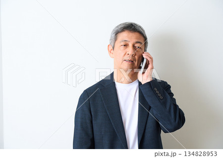 白背景で電話をするシニア男性 134828953