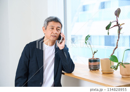 窓際で電話をするシニア男性 134828955