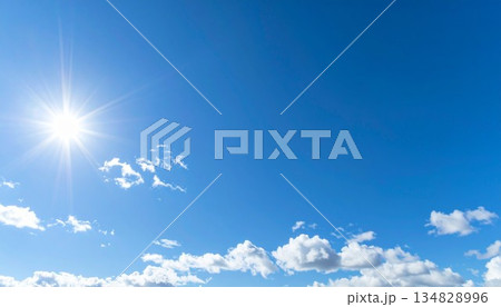 日差しのまぶしい真夏の青空。太陽と綿雲。 134828996