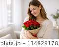 young woman holding a bouquet of red roses, soft smile, self love concept for Valentine's Day 134829178