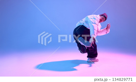 Street dancer performing dynamic pose in studio with colored light. Street dancer performing dynamic pose in studio with colored light. 134829771