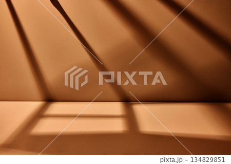 Warm brown studio background with dramatic diagonal light shadows creating minimal cinematic scene with strong depth and copy space Warm brown studio background with dramatic diagonal light shadows creating minimal cinematic scene with strong depth and copy space 134829851