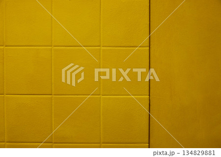Yellow padded wall texture with square geometric pattern, soft matte fabric surface, subtle depth, warm tone and clean minimal background. Copy space 134829881