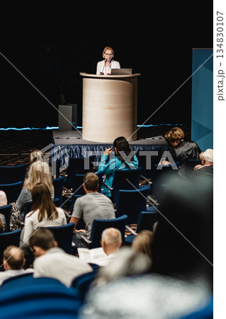 Female speaker giving a talk on corporate business conference. Unrecognizable people in audience at conference hall. Business and Entrepreneurship event Female speaker giving a talk on corporate business conference. Unrecognizable people in audience at conference hall. Business and Entrepreneurship event 134830107