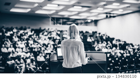 Female speaker giving a talk on corporate business conference. Unrecognizable people in audience at conference hall. Business and Entrepreneurship event Female speaker giving a talk on corporate business conference. Unrecognizable people in audience at conference hall. Business and Entrepreneurship event 134830110