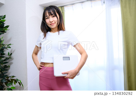 ヨガウェアで体重計を持つ笑顔の日本人女性　ダイエット　レギンス　 134830292