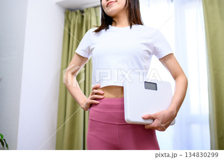 ヨガウェアで体重計を持つ笑顔の日本人女性　ダイエット　レギンス　 134830299