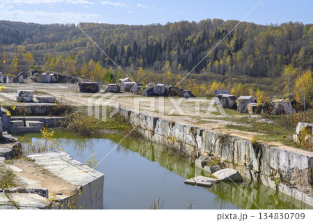 Huge geometric stone shapes and autumn birches reflected in the water of the abandoned marble quarry Huge geometric stone shapes and autumn birches reflected in the water of the abandoned marble quarry 134830709
