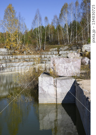Huge cubic and geometric stone shapes are reflected in the water of the abandoned marble quarry Huge cubic and geometric stone shapes are reflected in the water of the abandoned marble quarry 134830725