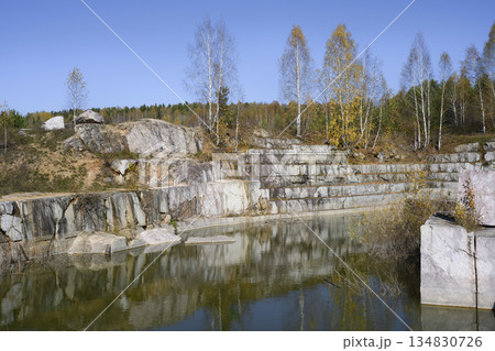 Huge cubic and geometric stone shapes are reflected in the water of the abandoned arble quarry Huge cubic and geometric stone shapes are reflected in the water of the abandoned arble quarry 134830726
