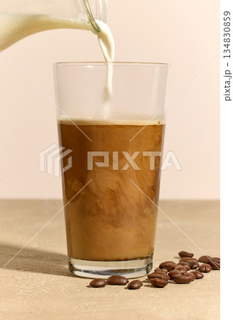 milk pouring in glass of coffee milk pouring in glass of coffee 134830859