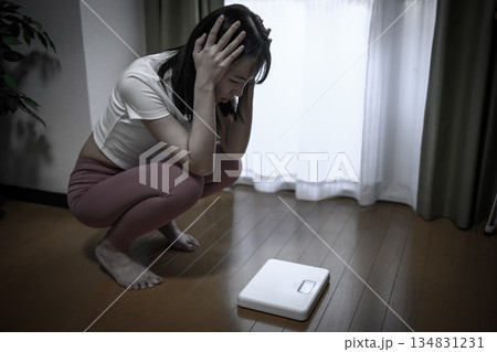 ヨガウェアで体重計を見てショックを受ける女性　ダイエット　レギンス　減色 134831231