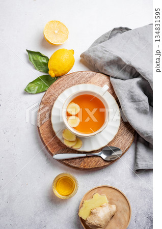 Cup of ginger lemon tea with honey and fresh ingredients on a light background. 134831595