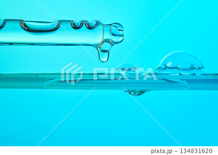 Dropper dispensing blue skincare liquid serum with bubbles 134831620