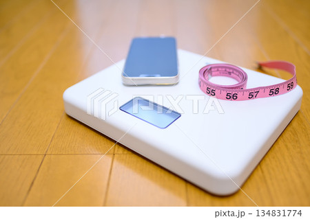 フローリングの上の体重計にスマホと巻き尺を置いて　計測イメージ 134831774