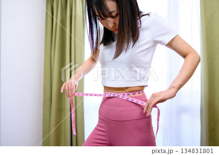 ヨガウェアでウエストをメジャーで測る日本人女性　ダイエット　レギンス　 134831801