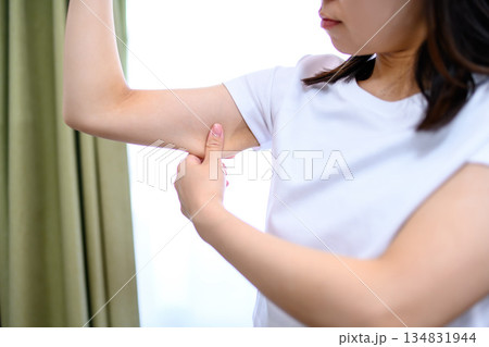 二の腕をつまんでたるみを確認する日本人女性　ダイエット　 134831944