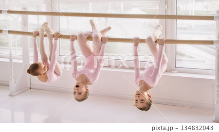 Young ballet students hanging on barre during stretching exercise in studio Young ballet students hanging on barre during stretching exercise in studio 134832043