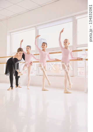Ballet teacher correcting foot position of young student 134832061