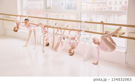 Children ballet class practicing flexibility exercises at barre 134832063