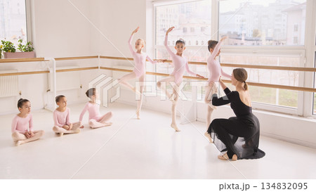 Children ballet class practicing turns and poses with instructor guidance 134832095