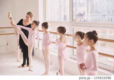 Ballet teacher demonstrating leg extension technique to students. 134832096