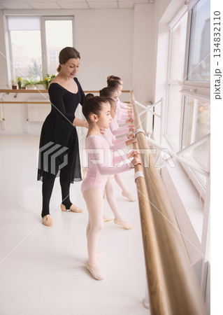 Ballet instructor guiding young dancer hand position during class 134832110