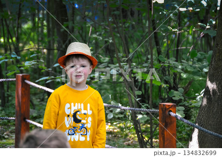 A boy wearing a yellow shirt and a hat is kneeling on a gravel road. High quality photo A boy wearing a yellow shirt and a hat is kneeling on a gravel road. High quality photo 134832699
