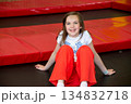 Happy girl having fun while jumping on trampoline. Sports girl jumps on a trampoline. Outdoor shot of girl jumping on trampoline, enjoys jumping in home. happy summer vacation. High quality photo 134832718