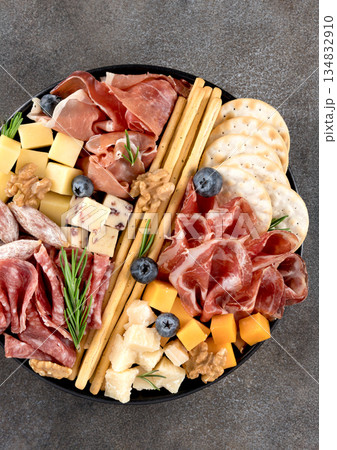 Charcuterie board with assorted cured meats, cheese, crackers, breadsticks, walnuts and berries. Party or wine snack. 134832910