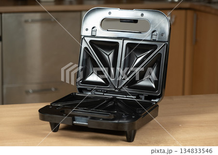 Open Electric Sandwich Toaster Appliance Ready to Use on a Wooden Kitchen Countertop. Open Electric Sandwich Toaster Appliance Ready to Use on a Wooden Kitchen Countertop. 134833546