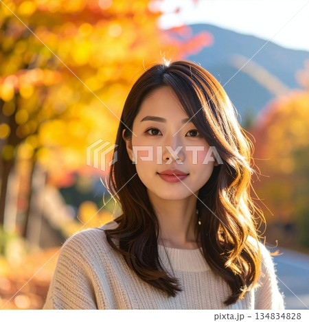 鮮やかな紅葉に包まれた秋の道で、柔らかな光に照らされる人物の場面 134834828