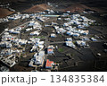 White buildings, town among volcanic black mountains and lava formations in Lanzarote, Canary Islands. 134835384
