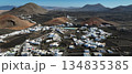 White buildings, town among volcanic black mountains and lava formations in Lanzarote, Canary Islands. 134835385