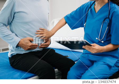 Senior Doctor discussing treatment with male patient talking and laughing sitting on examination bed Senior Doctor discussing treatment with male patient talking and laughing sitting on examination bed 134837474